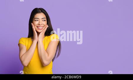 Tolles Angebot. Neugierige Asiatische Mädchen Suchen Beiseite Und Berühren Gesicht In Aufregung Stockfoto