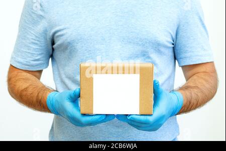 Kurier Hände in medizinischen Gummihandschuhe halten Kartons. Türzustellung. Lieferservice. Quarantäne. Stockfoto