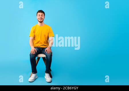 Studioaufnahme eines hübschen jungen Mannes, der auf dem Stuhl sitzt Stockfoto