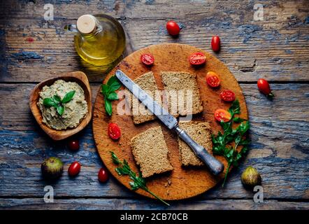 Draufsicht auf Auberginen Tahini Dip, Brot, Kirschtomate und Olivenöl auf Vintage Holztisch. Mediterrane Küche Stillleben. Hausgemachter Humus mit Bas Stockfoto