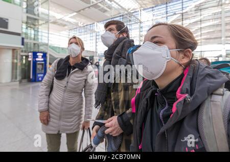 Familie am Flughafen München mit Schutzmaske auf der Suche nach Flüge Stockfoto