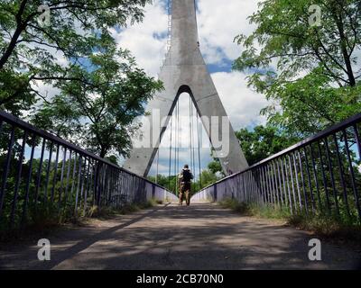 Ein Tourist mit Rucksack überquert im Sommer die Metallbrücke. Stockfoto