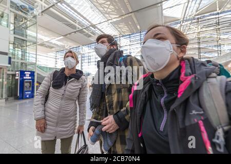 Familie am Flughafen München mit Schutzmaske auf der Suche nach Flüge Stockfoto