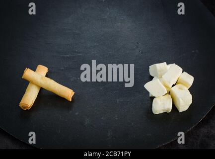 Türkische Stil Käse gefüllte Filo Teigbrötchen serviert zusammen mit Tomaten auf Salatblättern. Stockfoto