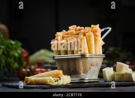 Türkische Stil Käse gefüllte Filo Teigbrötchen serviert zusammen mit Tomaten auf Salatblättern. Stockfoto