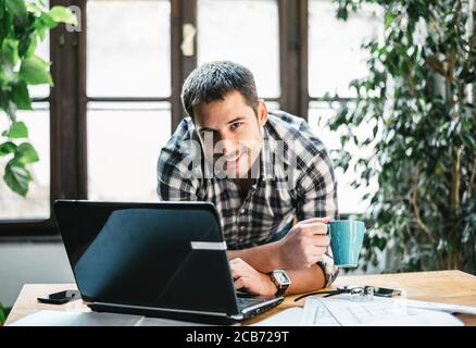Junger Mann arbeitet Remote in seinem coolen Home Office. Modernes Arbeitsraum-Studio für Online-Business und freiberufliche kreative digitale Projekte. Internet-Beruf Stockfoto