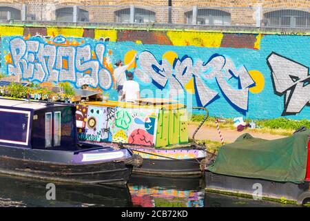 England London Stratford Park Hackney Wick Graffiti Mann Männer Malerei Briefe Wand Abschleppweg Stockfoto