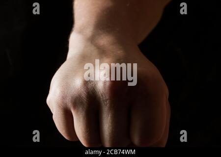 Hand geballt in eine Faust auf einem dunklen Hintergrund Konzept Von Streik und Selbstvertrauen aggressive Geste Stockfoto