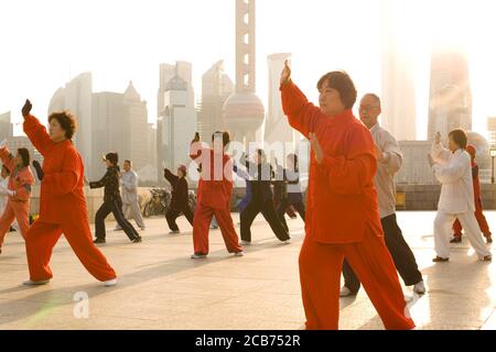 The Bund, Shanghai, China, Asien - Menschen üben Tai Chi bei Sonnenaufgang am Flussufer des Huangpu Flusses mit Pudong Skyline in Stockfoto