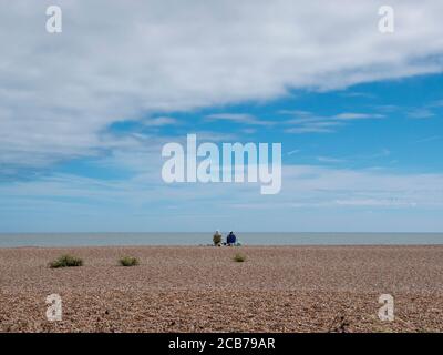 Zwei Leute sitzen am Kiesstrand allein in der Breite Open Space bei Aldeburgh Suffolk UK Stockfoto