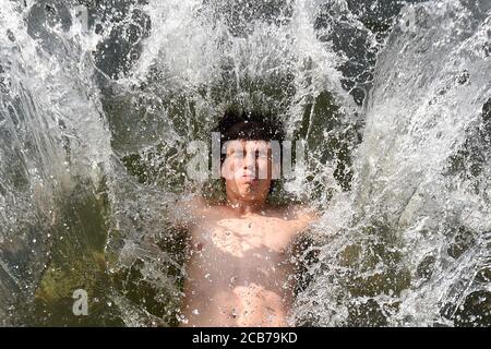 Owen Chisholm, 13, fällt von einem Ponton im Richmond Canoe Club in die Themse, während er das heiße Wetter in Richmond im Südwesten Londons genießt. Stockfoto