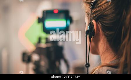 Hinter der Szene. Weibliche Kameramänin, die die Filmszene mit Kamera im Filmstudio dreht Stockfoto