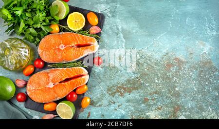 Flacher Lay von zwei Lachs rohen Steaks mit Kochzutaten Auf hellblauem cyanfarbenem Hintergrund Stockfoto