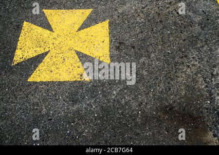 Gelbes malteserkreuz, Ambulanzparkplatz mit gelbem Symbol gekennzeichnet. Stockfoto