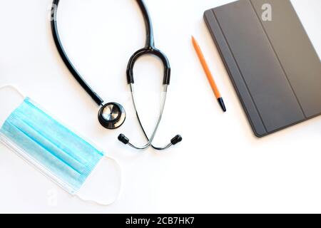 Arzttisch in der medizinischen Klinik. Stethoskop, Maske und digitales Tablet. Stockfoto