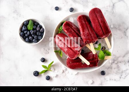 Draufsicht mit leuchtend roten Beereneis-Sorbet-Eis-Eiszapfen Weißer Marmorhintergrund Stockfoto
