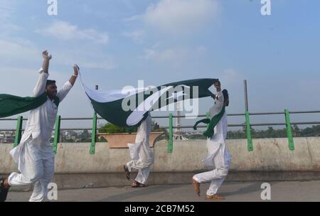 Lahore, Pakistan. August 2020. Pakistanische Jugendliche halten Nationalflagge und rufen Slogan gegen Greater Iqbal Park Verwaltung in Azadi Inter-Change in Lahore. Als Regierung wieder Parks, öffentliche Plätze, Schreine, Basare, Märkte, Restaurants im ganzen Land, die während der Corona-Virus Ausbruch geschlossen wurden, während Greater Iqbal Park Verwaltung sagte, dass sie jede offizielle Benachrichtigung über die Wiedereröffnung des Parks in Provinzhauptstadt erhalten. (Foto von Rana Sajid Hussain/Pacific Press) Quelle: Pacific Press Media Production Corp./Alamy Live News Stockfoto