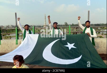 Lahore, Pakistan. August 2020. Pakistanische Jugendliche halten Nationalflagge und rufen Slogan gegen Greater Iqbal Park Verwaltung in Azadi Inter-Change in Lahore. Als Regierung wieder Parks, öffentliche Plätze, Schreine, Basare, Märkte, Restaurants im ganzen Land, die während der Corona-Virus Ausbruch geschlossen wurden, während Greater Iqbal Park Verwaltung sagte, dass sie jede offizielle Benachrichtigung über die Wiedereröffnung des Parks in Provinzhauptstadt erhalten. (Foto von Rana Sajid Hussain/Pacific Press) Quelle: Pacific Press Media Production Corp./Alamy Live News Stockfoto