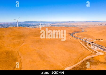 Luftaufnahme der Windturbinen und kurvige Straße weiter Wunderschöne goldene Berglandschaft in Kalifornien Stockfoto