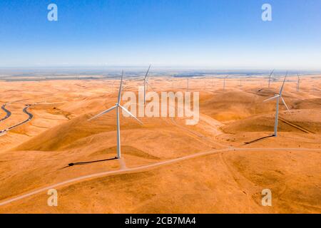 Luftaufnahme der Windturbinen und kurvige Straße weiter Wunderschöne goldene Berglandschaft in Kalifornien Stockfoto