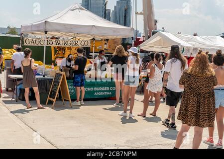 Am Eröffnungstag, Sonntag, 9. August 2020, erdulden die Käufer die Hitze auf dem Greenpoint Terminal Market. Der Markt behielt die extrabreiten Gänge aufrecht, eine Voraussetzung für Gesichtsbedeckung und soziale Distanzierungsprotokolle, da Käufer handwerkliche und antike Waren sowie eine Auswahl von Lebensmittelhändlern durchstöberten. (© Richard B. Levine) Stockfoto