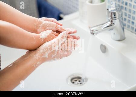 Mutter helfend Mädchen Kind waschen Hände zusammen im Bad Waschbecken Mit viel Seife unter fließendem Wasser Stockfoto