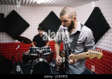 E-Gitarrist und Schlagzeuger hinter dem Schlagzeug Stockfoto