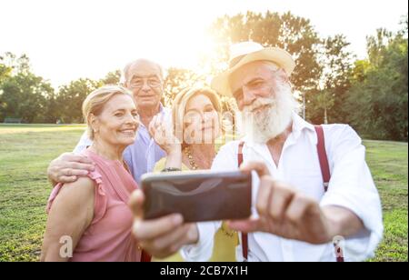 Gruppe von Senioren, die ein Picknick im Park machen und Spaß haben. Selfies mit Freunden aufnehmen Stockfoto