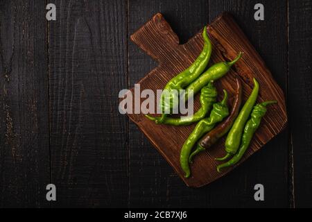 Scharfe grüne Chilischoten auf Teak Holz Schneidebrett, dunkle Holz Hintergrund, Draufsicht Copy Space Stockfoto