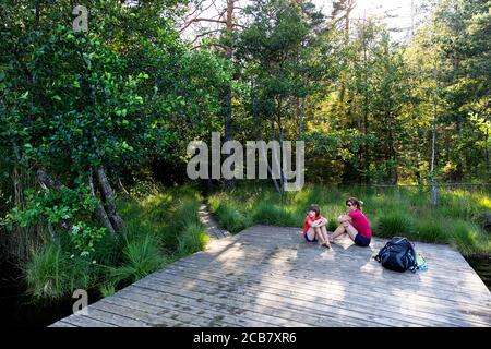 Mutter und Sohn sitzen auf Holzsteg am Egelsee, Österreich, Oberösterreich, Oberösterreich Stockfoto