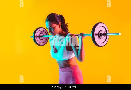 Frau trainiert mit Langhanteln im Fitnessstudio Stockfoto