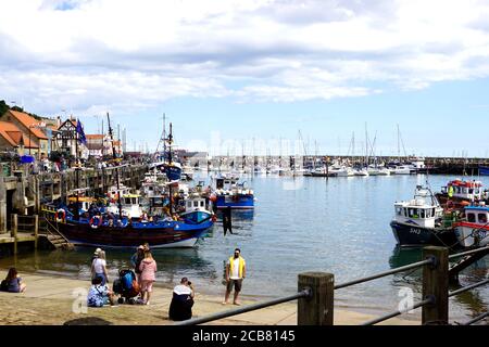 Scarborough, Yorkshire, Großbritannien. 03. August 2020. Touristen und Urlauber, die den Kai und die Slipanlage des Hafens von Scarborough in Yorkshire genießen, Stockfoto