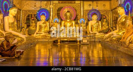 Yangon, Myanmar - 18. Dezember 2017: Ein birmanischer buddhistischer Mönch betet in einem Raum mit Buddhas an der Shwedagon Pagode Stockfoto