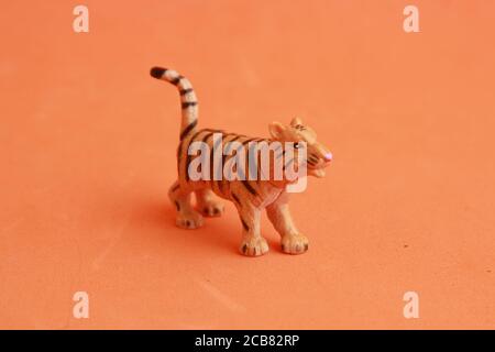 Kleines Gummi-Tiger-Spielzeug isoliert auf einem orangen Hintergrund Stockfoto