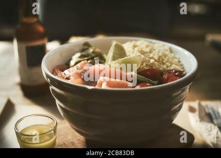 Schüssel Lachs, Tomaten und Cous-Cous-Salat mit einem Glas Bier Stockfoto