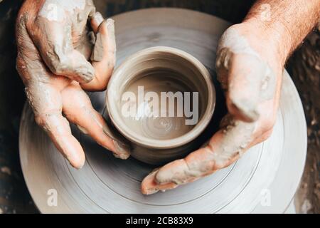 Potters Hände arbeiten Ton auf einem Töpferrad Stockfoto