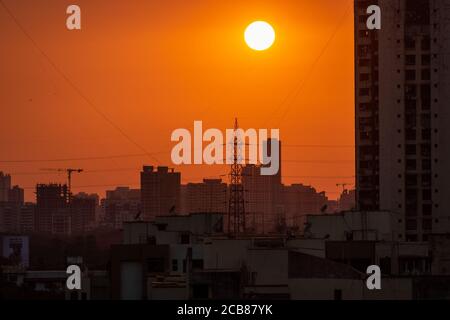 Mumbai, Maharashtra, Indien - März 2020: Der Sonnenuntergang über einem elektrischen Mast und die hohen Hochhäuser des Vororts von Kandivali Ost in Mumbai. Stockfoto