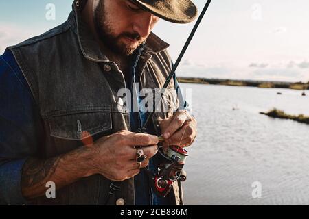 Vater zeigt Sohn, wie Angelrute verwenden. Hintergrund blauer See Stockfoto