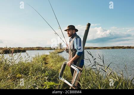 Vater zeigt Sohn Angelplatz und gehen, um ihn zu lehren, wie man fischen. Tag sonnig. Hintergrund blauer See. Stockfoto