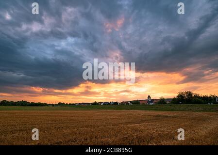 Farbenprächtiger Abendhimmel über Weizenfeldern in der Nähe eines Dorfes in der Nähe von Regensburg Stockfoto