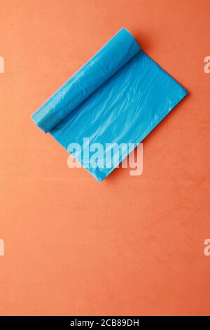 Vertikale Nahaufnahme einer Rolle blauer Müllsäcke Auf einem orangefarbenen Hintergrund Stockfoto