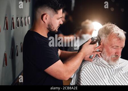 Professionelle Stylistin dabei Styling mit dem elektrischen Rasierer. Nahaufnahme Seitenansicht Foto. Beruf, Beruf, Job Stockfoto