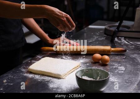 Der Küchenchef bereitet Gebäck in einer professionellen Küche zu. Dunkler Hintergrund. Stockfoto