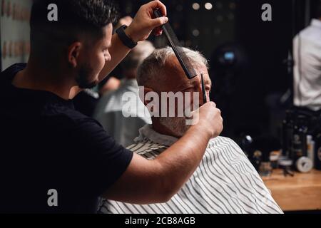 Junge Maste schneiden die ungeraden Haare, Nahaufnahme Seitenansicht Foto Stockfoto