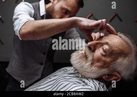 Respektable ältere kaukasischen Mann Besuch hairstylist in Friseur für die Rasur und neues Design für seine grauhaarige Bart Stockfoto