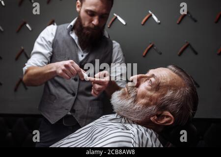 Caucasin alter Mann seinen Bart abrasiert bekommen von Friseur Besuch hairtician bei der Rasur Limousine, in der Nähe Stockfoto