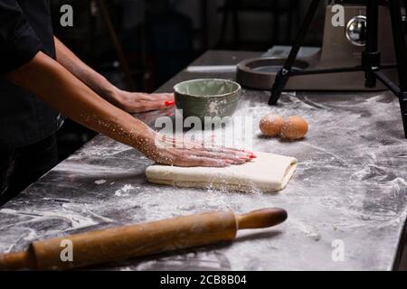 Der Küchenchef bereitet Gebäck in einer professionellen Küche zu. Dunkler Hintergrund. Stockfoto