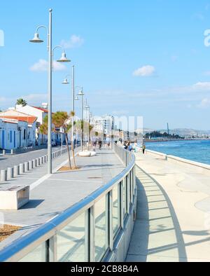 Menschen, die am Stadtdamm von Larnaca mit typischen Architekturgebäuden in weißer Farbe bei strahlendem Sonnenschein, Zypern, spazieren gehen Stockfoto