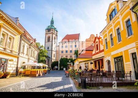 Melnik, Tschechische Republik - 29.07.2020: Alte Straße bei Sonnenuntergang mit Cafés und Uhrturm der Kirche der Heiligen Peter und Paul, Melnik, Tschechische republik Stockfoto