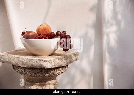 Stillleben einer Schüssel mit Früchten mit weißem Stoff als Hintergrund im Freien genommen. Stockfoto